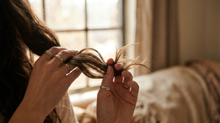 Hands holding a section of textured hair up to the light to inspect split ends and breakage